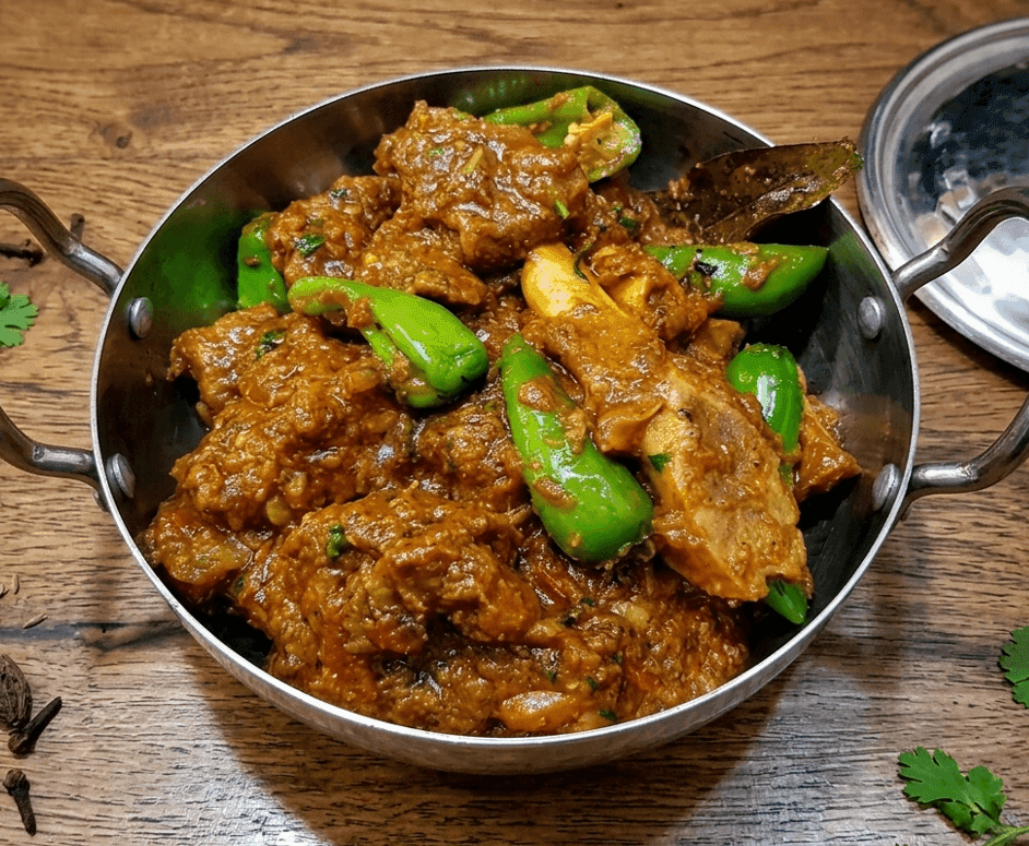 Traditional Balti Gosht goat curry with rich spiced gravy in a round-bottomed balti pot