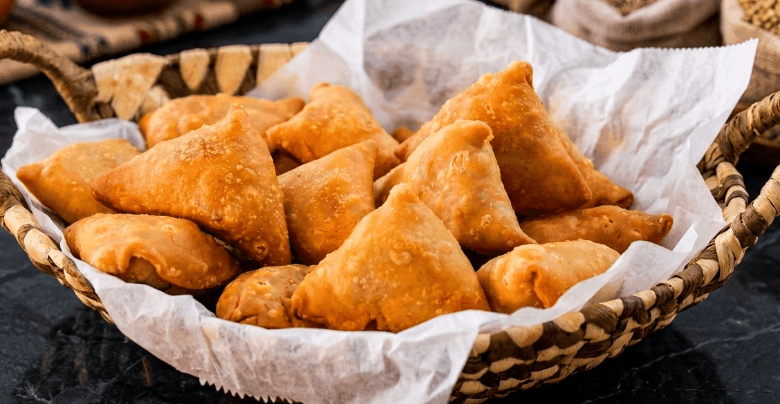 Crispy golden aloo samosas with handmade dough, halved to show spiced potato filling
